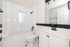 Full bathroom with vanity, toilet, tile walls, tile patterned floors, and tiled shower / bath combo