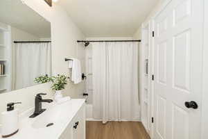 Full bath featuring shower / bath combo with shower curtain, wood finished floors, and vanity