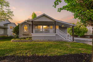 Ranch-style house featuring covered porch, a front yard, stone siding, stucco siding, and stairway