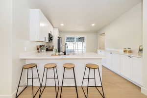 Kitchen featuring a peninsula, a breakfast bar area, white cabinetry, a sink, and appliances with stainless steel finishes