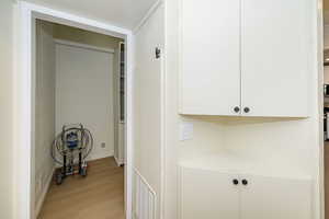 Hallway with baseboards, light wood-style flooring, and visible vents