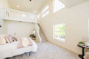 Bedroom with high vaulted ceiling, multiple windows, and carpet flooring