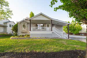 Ranch-style home featuring a front lawn, stone siding, stucco siding, a porch, and stairway