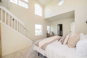 Carpeted bedroom with high vaulted ceiling and baseboards