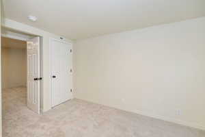 Unfurnished bedroom with baseboards and light colored carpet
