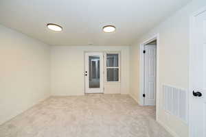 Unfurnished room featuring baseboards, visible vents, and light carpet