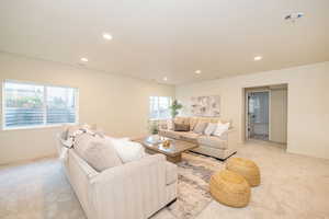 Living room featuring recessed lighting, baseboards, visible vents, and light carpet