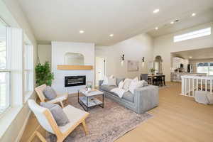 Living room with recessed lighting, arched walkways, a large fireplace, and light wood finished floors
