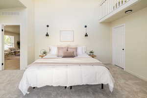 Bedroom featuring a high ceiling, light colored carpet, baseboards, and visible vents