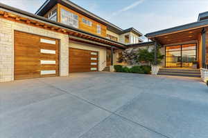 View of front of house featuring stucco siding, stone siding, a garage, and concrete driveway