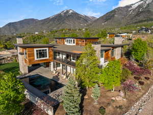 Rear view of house with a chimney, a mountain view, a balcony, and an outdoor pool