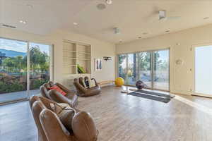 Living area with a healthy amount of sunlight, wood finished floors, and ceiling fan