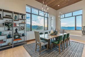 Dining room with a mountain view, baseboards, wooden ceiling, a chandelier, and wood-type flooring