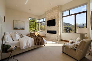 Bedroom featuring carpet flooring, a stone fireplace, and baseboards