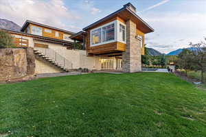 Rear view of house featuring a lawn, a mountain view, a patio area, and stairs