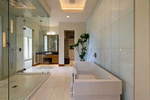 Bathroom featuring a stall shower, tile patterned flooring, vanity, a tub to relax in, and a spacious closet