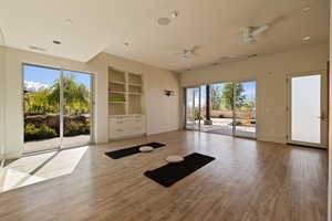Exercise area featuring a ceiling fan, wood finished floors, built in features, and baseboards