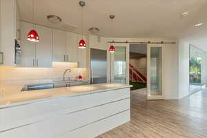 Kitchen with a sink, hanging light fixtures, light wood-style flooring, and stainless steel appliances
