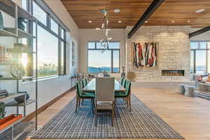 Dining room with a stone fireplace, recessed lighting, wooden ceiling, wood finished floors, and baseboards