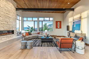 Living area featuring a stone fireplace, beam ceiling, and wood finished floors