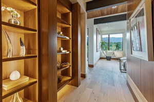 Hall with light wood-style flooring, baseboards, and built in features