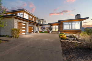 View of front of house featuring concrete driveway, a chimney, and an attached garage