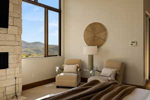 Bedroom with a stone fireplace, baseboards, and a mountain view