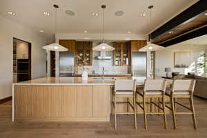 Kitchen featuring modern cabinets, multiple ovens, decorative backsplash, a spacious island, and recessed lighting