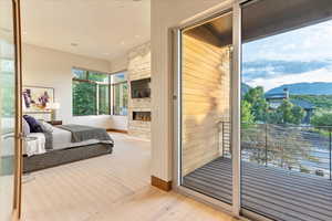 Bedroom with a stone fireplace and light wood-style floors