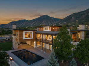 Rear view of property with a patio, a mountain view, a chimney, an outdoor pool, and a garage