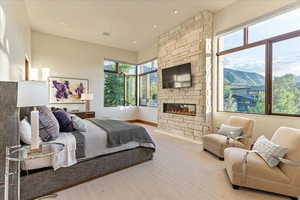 Carpeted bedroom with baseboards and a stone fireplace