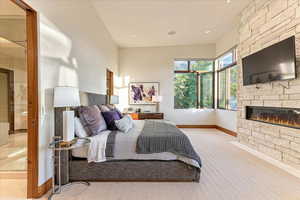 Carpeted bedroom featuring a fireplace and baseboards
