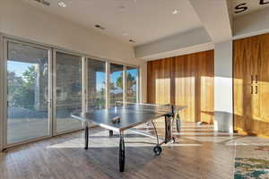 Recreation room with recessed lighting, wooden walls, visible vents, and wood finished floors