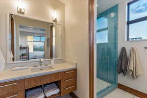 Bathroom with a stall shower, vanity, and baseboards
