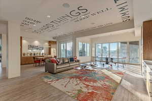 Living room with baseboards, light wood finished floors, and recessed lighting