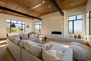 Living room with wood ceiling, wood finished floors, beam ceiling, a stone fireplace, and recessed lighting