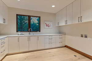Kitchen featuring baseboards, light wood-style floors, white cabinetry, and light countertops