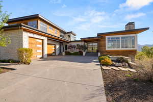 Contemporary house with driveway, a chimney, and an attached garage