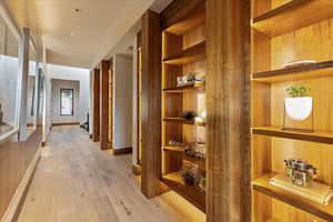 Corridor featuring light wood-style floors, built in features, baseboards, and stairs
