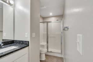 Bathroom with vanity, tile patterned floors, a stall shower, and toilet