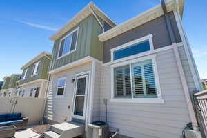 Rear view of property featuring central AC, board and batten siding, and fence