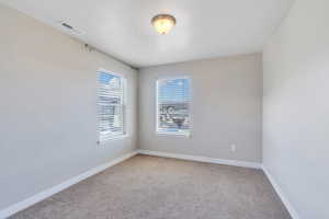 Unfurnished room featuring carpet floors, baseboards, and visible vents