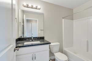 Full bath featuring toilet, baseboards, tub / shower combination, and vanity
