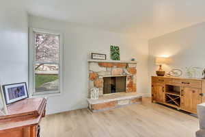Living room featuring baseboards, a stone fireplace, and wood finished floors