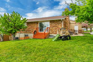 Back of property featuring a chimney, a lawn, a patio area, brick siding, and entry steps
