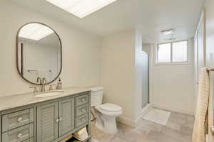 Bathroom featuring vanity, visible vents, toilet, baseboards, and a stall shower
