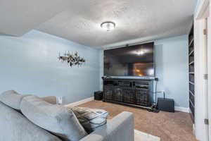 Carpeted living room with baseboards and a textured ceiling
