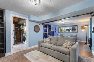 Living room featuring baseboards, a textured ceiling, and washer / dryer