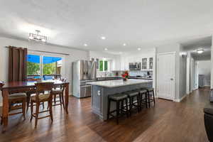 Kitchen featuring glass insert cabinets, a center island, dark wood-type flooring, white cabinetry, and stainless steel appliances