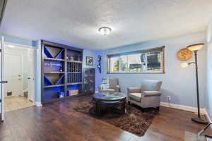 Living area with a textured ceiling, baseboards, and hardwood / wood-style flooring